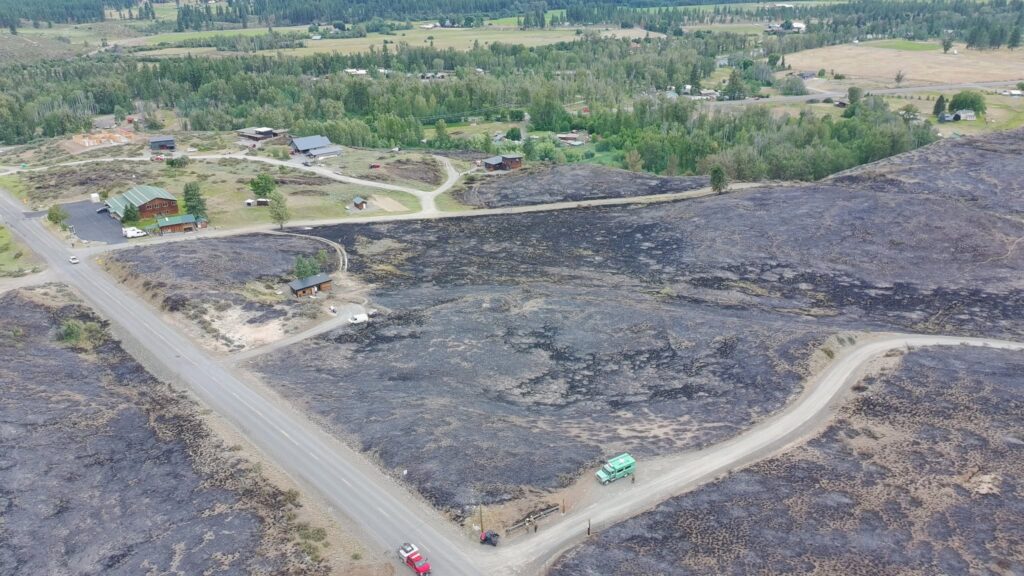 Aerial shot of a rural wooded community after a wildfire with burn scars on the landscape